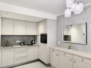 a white kitchen with white cabinets and a mirror at Sunshine Residence Boutique Apartment in Hévíz