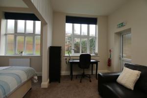 a bedroom with a bed and a desk and windows at Hendford Apartments in Yeovil