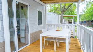 a white porch with a white table and chairs at Happy Camp mobile homes in Camping Bella Italia in Peschiera del Garda