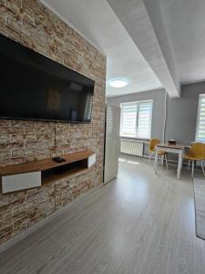 een woonkamer met een televisie aan een bakstenen muur bij Квартира-студия рядом с Набережной in Balqash