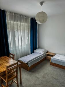 Un dormitorio con dos camas y una mesa y una ventana. en Hostel Demi, en Cracovia