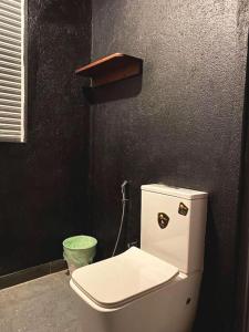 a bathroom with a white toilet in a black wall at Athyantha Resort in Anuradhapura