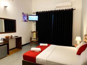 a bedroom with a bed and a desk and a television at Athyantha Resort in Anuradhapura