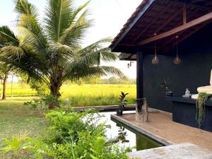 a house with a palm tree and a pond at Athyantha Resort in Anuradhapura