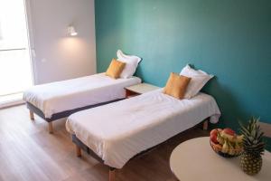 two beds in a room with a green wall at Terres de France Brest in Brest
