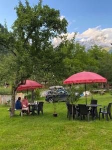 two people sitting at tables under red umbrellas at Guest House Mariami in Ushkhvanari +49 photos