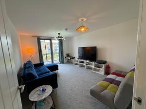 a living room with a couch and a tv at Beautiful Newbuild 5 bedroom Town House in Chelmsford