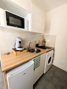 a small kitchen with a sink and a microwave at Studio *Sérénité* in Villejuif +6 photos