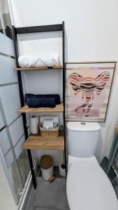 a bathroom with a toilet and shelves with towels at Studio *Sérénité* in Villejuif