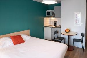 a bedroom with a bed and a table and a kitchen at Terres de France Brest in Brest