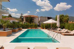 a swimming pool with chairs and an umbrella at Palacio Verde in Asprovalta