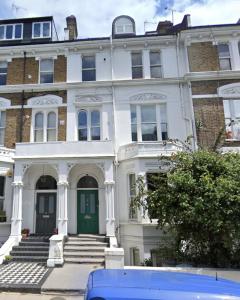 a white house with a green door on a street at Kensington Bay View Dreams in London