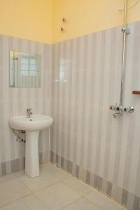 Un baño con un lavabo blanco y un espejo. en Legacy Homes, en Mutomo