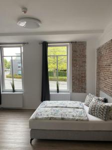 a bedroom with a bed and two windows at Appartementhaus EMDEN in Emden