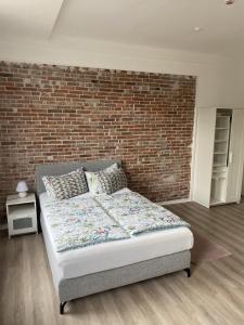 a bed in a room with a brick wall at Appartementhaus EMDEN in Emden