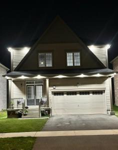 a house with a white garage at night at Top of the Chain Home Palace- CA in Thorold