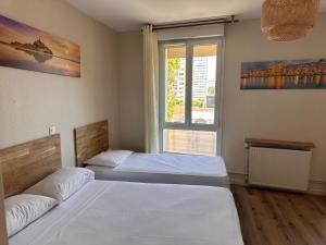 two beds in a room with a window at HOTEL IN PARIS in Aubervilliers +21 photos