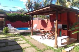 un patio con tavolo, sedie e una casa di Linda Casa em Boiçucanga - São Sebastião, 4 suítes a São Sebastião