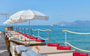 a row of beach chairs and umbrellas on a pier at Hôtel Barrière Le Gray d'Albion in Cannes