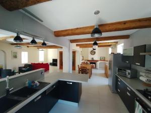 a kitchen with black cabinets and a living room at Les 27 in Ginestas