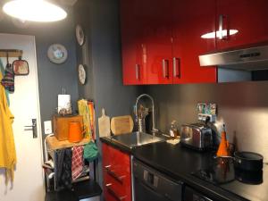 a kitchen with red cabinets and a sink at Chambre et salle d'eau proches du Sacré-Coeur in Paris