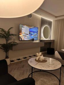 un salon avec une table et une télévision au mur dans l'établissement أستديو Studio Hiten- Boulevard, à Riyad