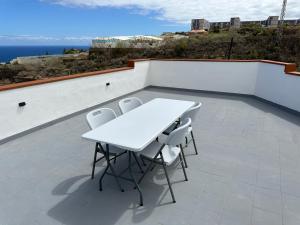 a white table and chairs sitting on a roof at New modern apartment, Scandinavian style, ocean view, huge terrace in Icod de los Vinos