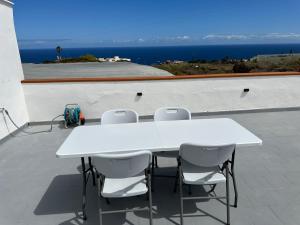 a white table and chairs on a roof with the ocean at New modern apartment, Scandinavian style, ocean view, huge terrace in Icod de los Vinos