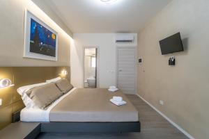 1 dormitorio con 1 cama grande y TV en la pared en Giardini Inn arte, en Giardini Naxos