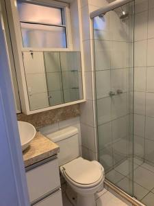 a bathroom with a toilet and a glass shower at Beach Village - Praia do Futuro II in Fortaleza