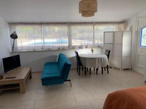 a living room with a table and a blue chair at Studio le soleil couchant in Saint-Saturnin-lès-Avignon