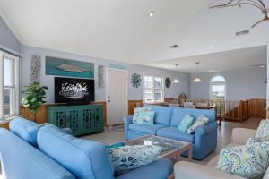 een woonkamer met blauwe banken en een tv bij SNH249 SeaAira in Nags Head