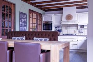 a kitchen with a wooden table and a kitchen with white cabinets at Waterhill's Bed in Dinteloord