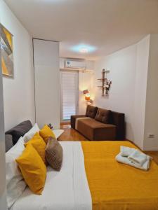 a bedroom with a bed with yellow pillows and a couch at Kamche apartment in Skopje