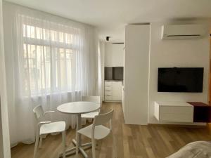 Habitación blanca con mesa, sillas y TV. en Lovely apartment in the city centre, en Bratislava