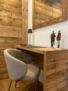 a desk with a chair and two figurines on it at Hotel Corona Ferrea in Sappada