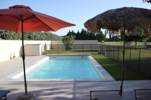a swimming pool with two umbrellas next to at Mas Aubert in Eyragues