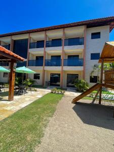 an apartment building with a playground in front of it at Flat Casa da Praia in Porto De Galinhas