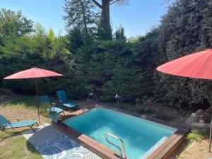 a swimming pool with two chairs and an umbrella at Bastide de la Couloubre in Mallemort