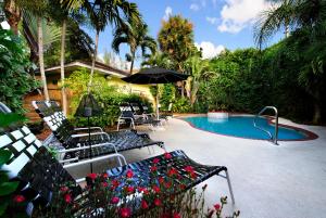 a swimming pool with chairs and an umbrella at Mango Inn Bed and Breakfast in Lake Worth