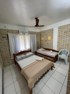 a bedroom with two beds and a chair in it at Pousada Ramo de Acácia in Bombinhas +45 photos