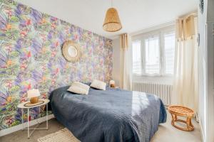Un dormitorio con una cama azul y una pared colorida en Maison Chaleureuse Cancale, en Cancale