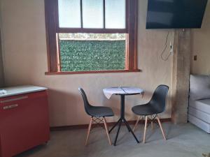 a room with two chairs and a table and a window at Suite Ana - Casa Tapera Nova in Conceição da Ibitipoca