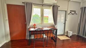 a dining room table with chairs in front of a window at Van Vliet Hostel in Phra Nakhon Si Ayutthaya
