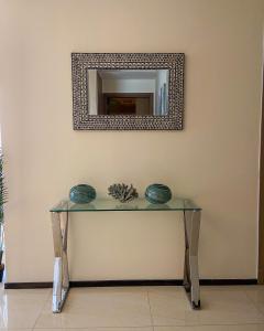 een spiegel aan een muur met een glazen tafel bij GTC Residence in Nairobi