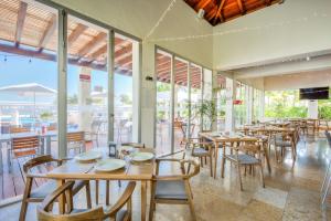 Un restaurante con mesas y sillas de madera y ventanas. en Increíble dpto de lujo con acceso a club de playa, en Cancún