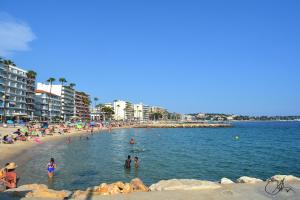 a beach with a bunch of people in the water at chambres d'hôtes en rez de villa piscine climatisation plage à pieds in Antibes