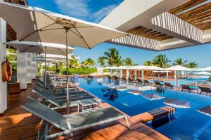 una piscina al aire libre con sillas y sombrillas en Increíble dpto de lujo con acceso a club de playa, en Cancún
