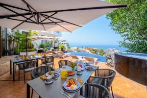 an outdoor dining area with tables and chairs and an umbrella at Villa Divina Luxury Boutique - Adults Only in Puerto Vallarta