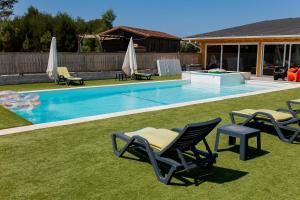a swimming pool with lawn chairs and a table and a swimming pool at Gothes Chalet Javier in Ponte de Vagos